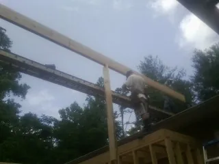 Carpenter setting a ridge beam over a new addition frame — Ice Dam Removal by Roofing Brothers in Babylon