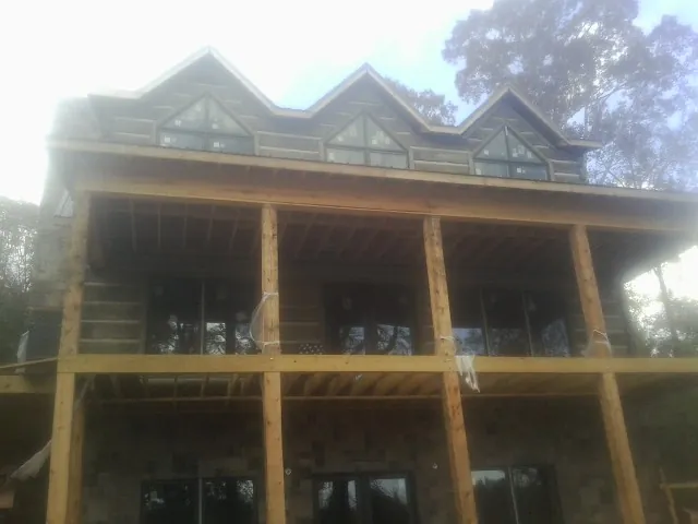 Dormers and porch framing on a large log home under construction — Roof Coating work by our crew in Babylon