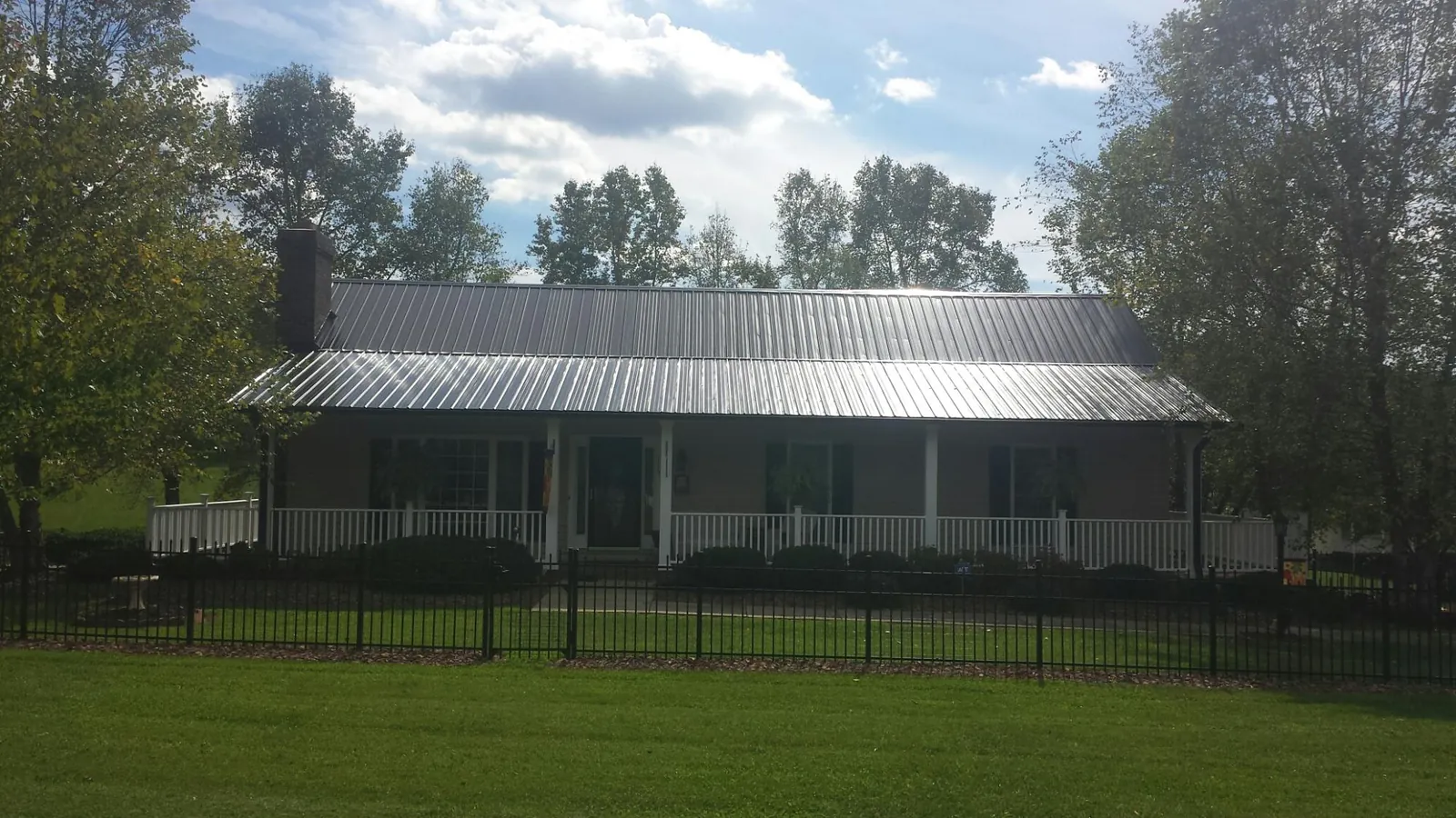 Gray metal roof on a brick ranch with a full width front porch — Gutter Guard Installation work by our crew in Babylon