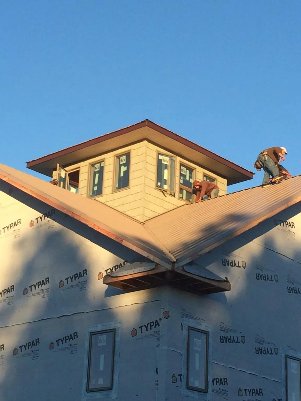 Roofers working around a rooftop cupola on a new metal roof at sunset — Roof Waterproofing in Babylon by Roofing Brothers